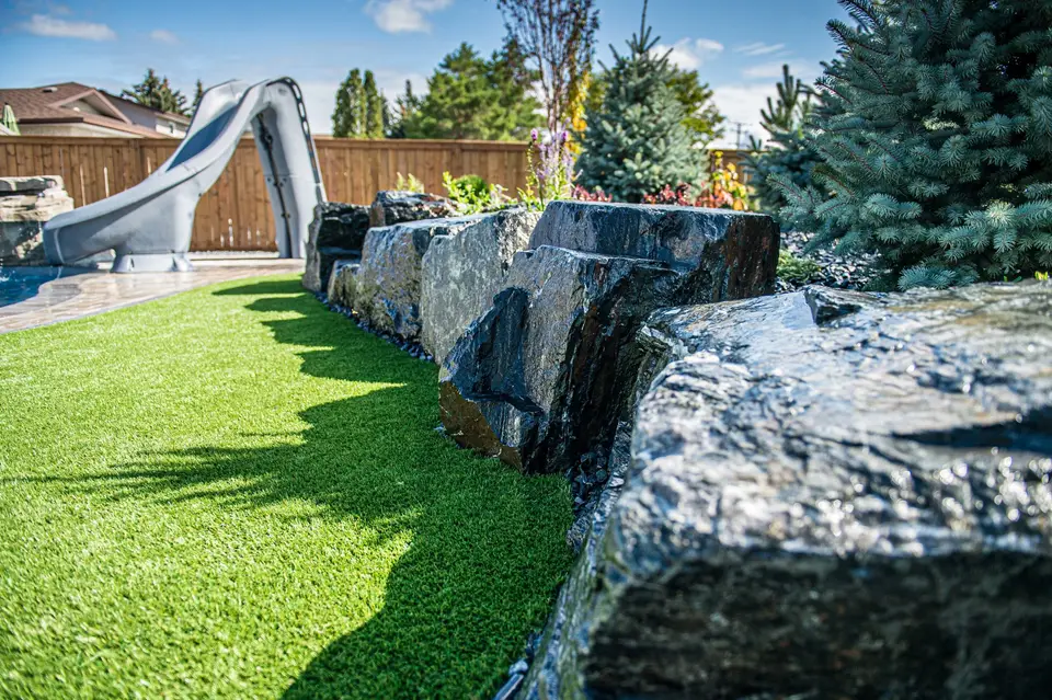 Boulder wall beside an artificial turf lawn